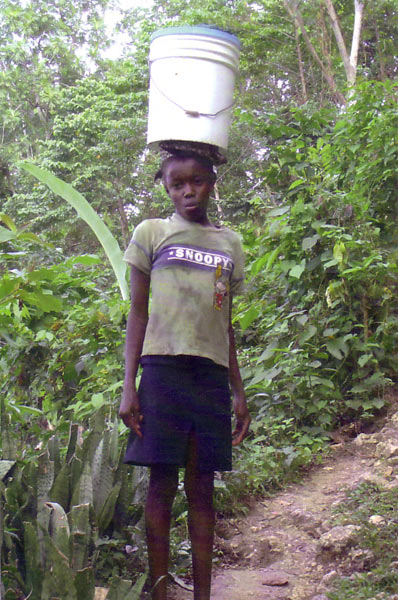 Niña cargada con un cubo de agua